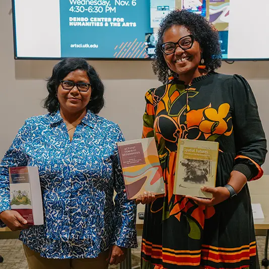 Two women posing for a photo while holding books