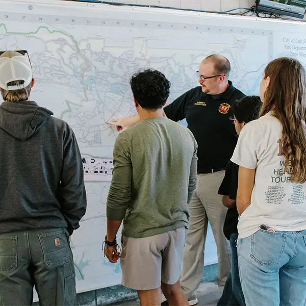 A man shows a group of people a wall map